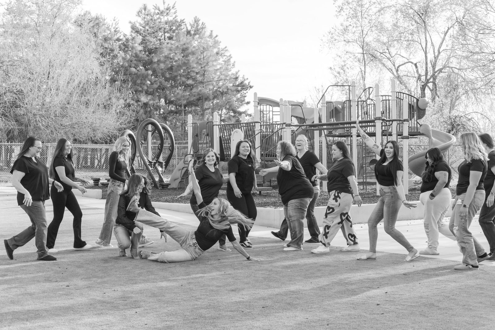 The Kids & Co team laughing and dancing together on the playground